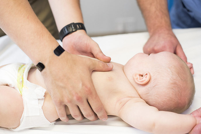 teaching thumbs CPR technique on infant